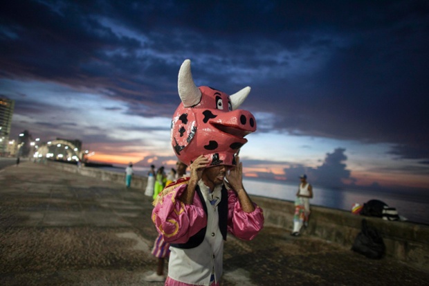 Havana. Cuba: A reveller removes his mask before performing at a carnival parade.