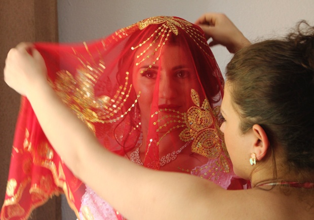 A red headscarf is placed over bride Vlora Jonuzi's head during her wedding in the village of Nerodime, Kosovo
