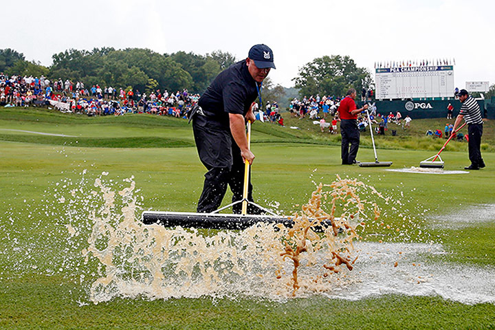 Rory McIlroy US PGA Open: Course workers push rain water off the first hole during a weather delay