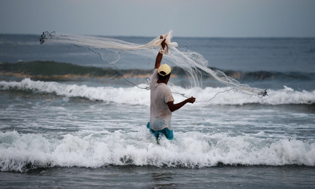 A Palestinian fisherman casts his net as he wades in to the sea near Gaza City