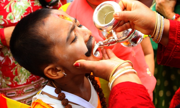 A child in traditional costume receives milk during the festival of cows or Gaijatra Festival, in Kathmandu, Nepal