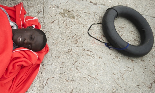 Sub-Saharan African migrants lies on the ground at Tarifa harbour