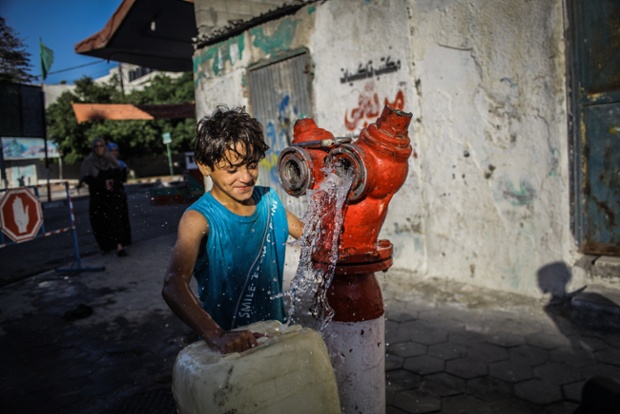 A child draws water from a tap in Gaza during a temporary ceasefire