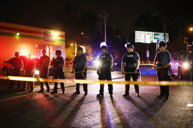 Police stand in an area Ferguson, Missouri last night after a black teenager, Michael Brown, was killed on Saturday