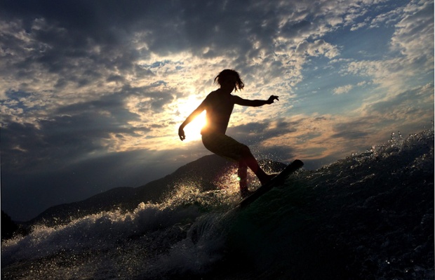 Zak Harman of North Vancouver is silhouetted by the setting sun as he wake surfs on Sprout Lake near Port Alberni, British Columbia, Canada.