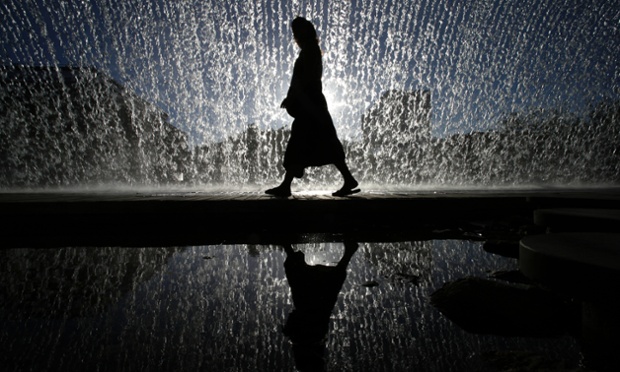 A woman walks under an artificial waterfall outside the Oceanarium in Lisbon, Portugal
