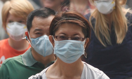 People wearing masks cross a street in Singapore's Orchard Road Shopping Area in June 2013