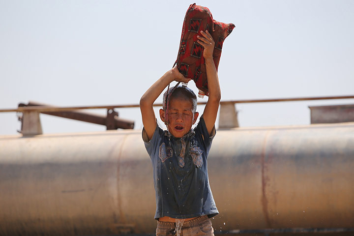 20 Photos: A young Iraqi Yazidi refugee pours water on himself in Hasaka, Syria