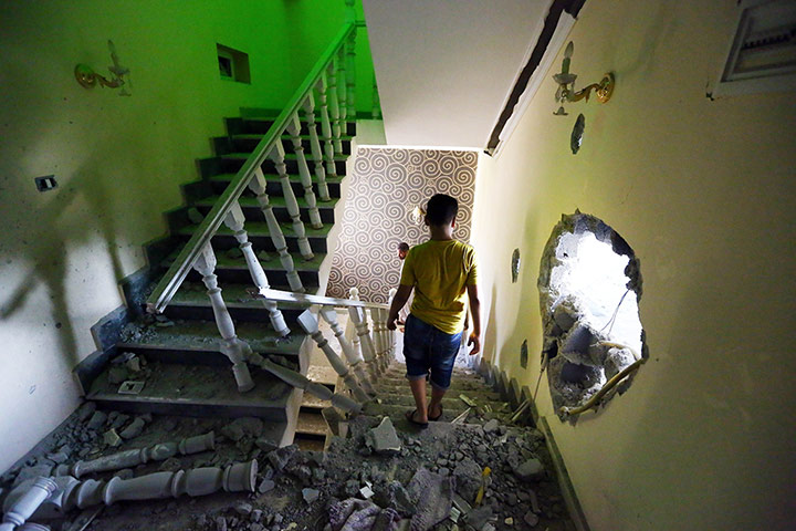 20 PHOTOS: A youth walks down the stairs near a hole in the wall of a house in Tripoli