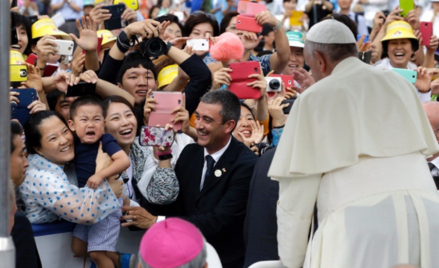 A crying child is held to be blessed by the pope at the closing Holy Mass of the 6th Asian Youth Day in Haemi Castle, South Korea.