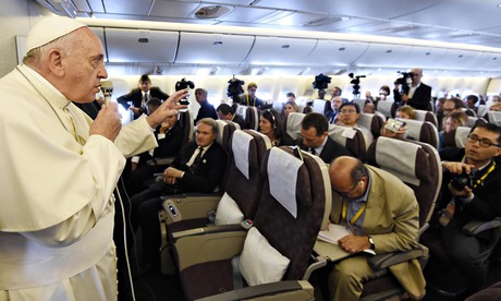 Pope Francis gestures while aboard a flight