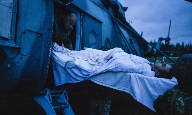 Ukrainian soldiers load a wounded man aboard a helicopter, near the eastern Ukrainian city of Shchastya, Lugansk region, on August 18, 2014. Ukraine accused pro-Russian rebels of killing dozens of civilians fleeing the war-torn east on August 18, 2014 as crisis talks between Kiev and Moscow failed to halt months of bloodshed.
