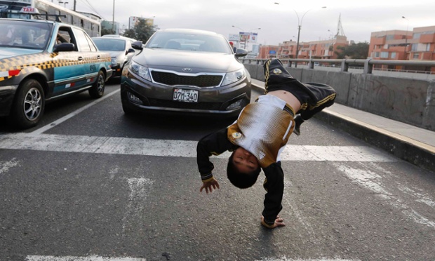 Nine-year-old Gianpierre somersaults at a traffic junction in the San Borja district in Lima. 