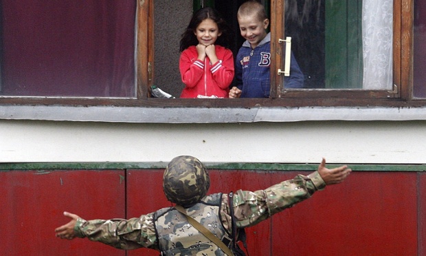A Ukrainian soldier gestures as he talks with children in Popasna