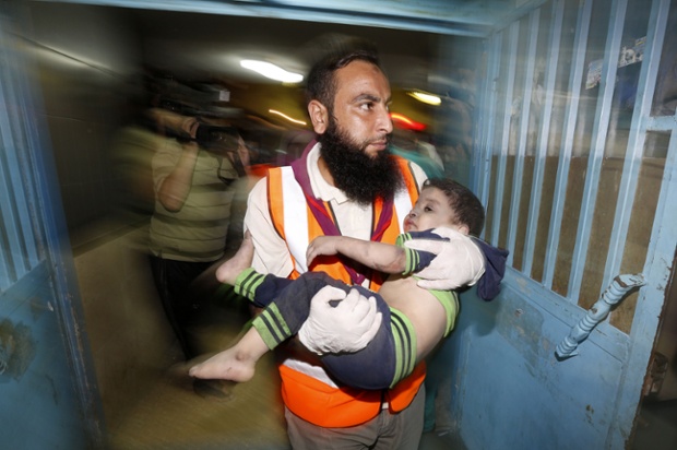 Palestinian doctor carries a wounded child at the Shifa hospital following an Israeli air strike on a house in Gaza City. The Israeli air strike killed a young girl and a woman, wounding 16 other people.