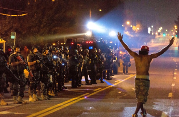 A protestor holding his hands up chants 'Hands up, don't shoot' as SWAT police unit stands guard during protests against police killing of Michael Brown in Ferguson, Missouri, United States.