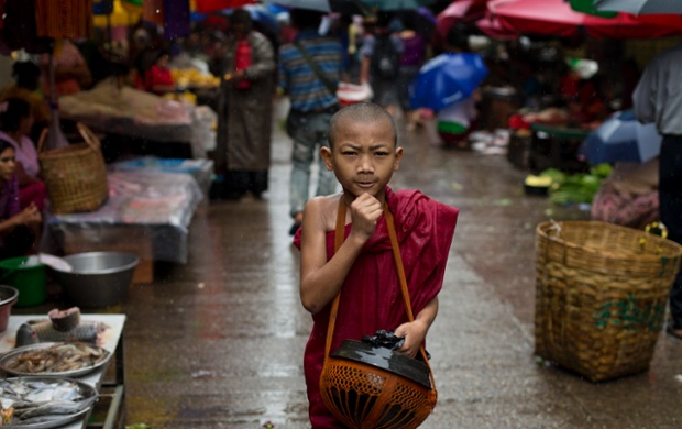 A novice Buddhist monk walks through a market in Yangon, Burma