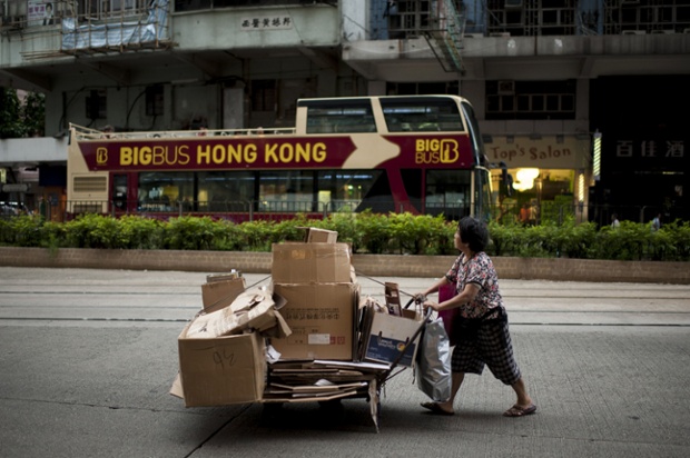 A woman pushes a cart of cardboard boxes though a Hong Kong street