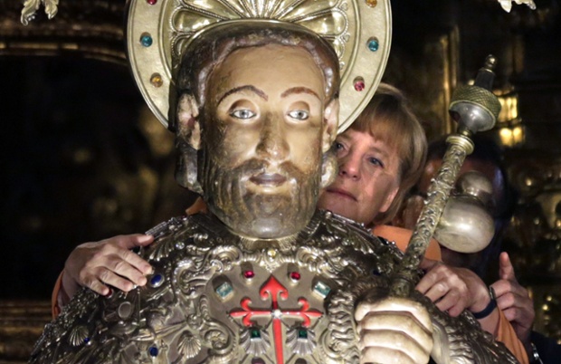 German Chancellor Angela Merkel embraces the statue of Saint James during her visit to the cathedral in Santiago de Compostela, Spain