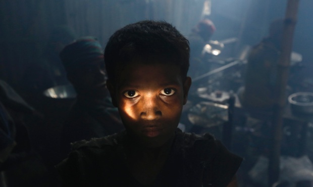A child worker poses during a break as he makes aluminium bowls at a small factory in Dhaka, Bangladesh