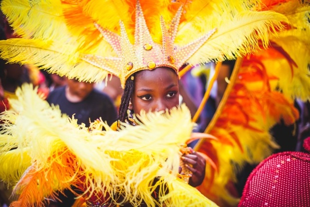 a girl performing at the notting hill carnival covering her face with her costume