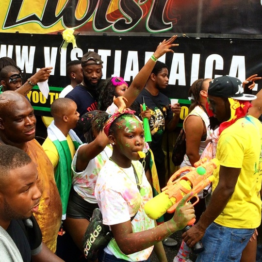 people dancing in the street with paint on their faces blowing whistles and holding a toy water gun