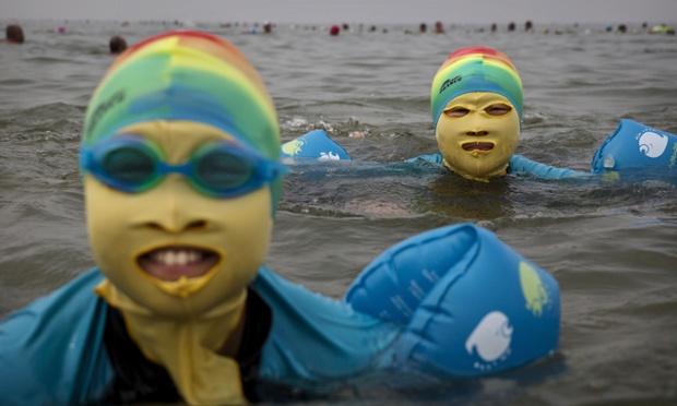 A mother and daughter wear face-kinis while swimming in the Yellow Sea in Qingdao, China