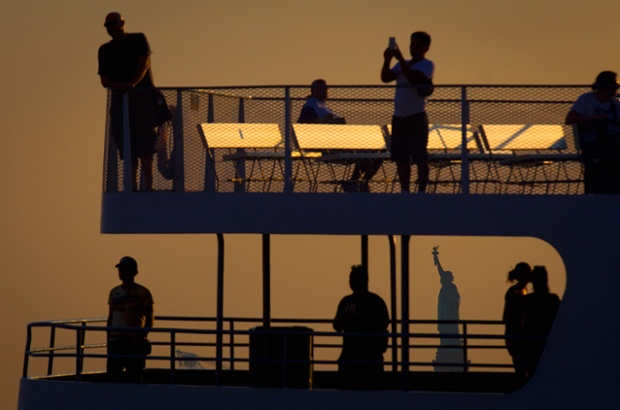 The Statue of Liberty is framed by a tour boat in the harbor, at the Manhattan borough of New York