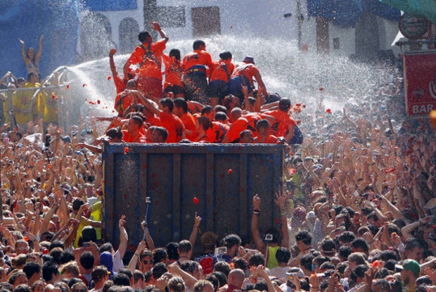 Crowds of people throw tomatoes at each other, during the annual 