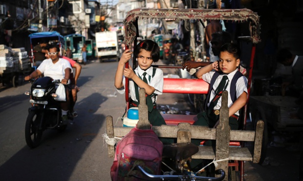 School children sit in a cycle rickshaw as they wait for the rickshaw-puller during the morning in the old quarters of Delhi