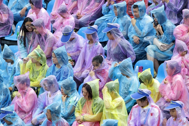 Spectators watch the beach volleyball in the rain during the Nanjing 2014 Youth Olympics in China