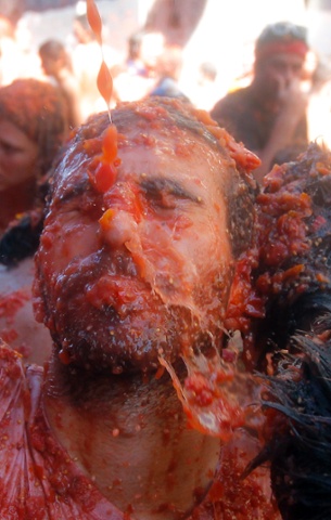 A man reacts as he is hit with tomatoes at La Tomatina