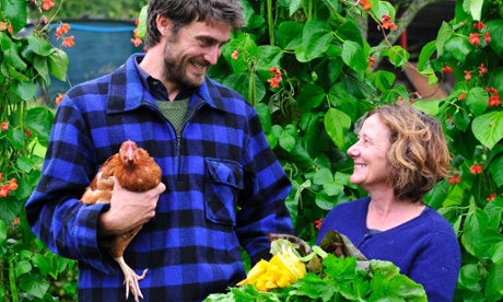 Two farmers in a field: one holds a chicken and the other holds a bunch of flowers...