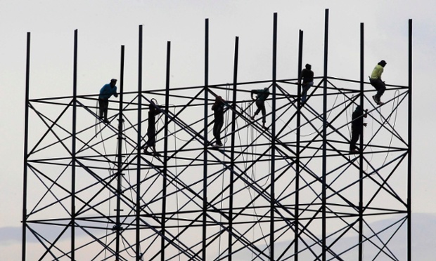 Men are balancing on steel beams to build the frame of a billboard on the coast of Cavite city, south of Manila, Philippines.