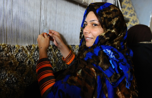 An inmate smiles as she weaves a carpet