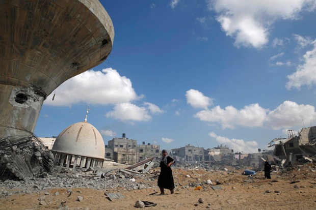 A Palestinian woman walks past a mosque damaged by Israeli strikes in the southern Gaza Strip