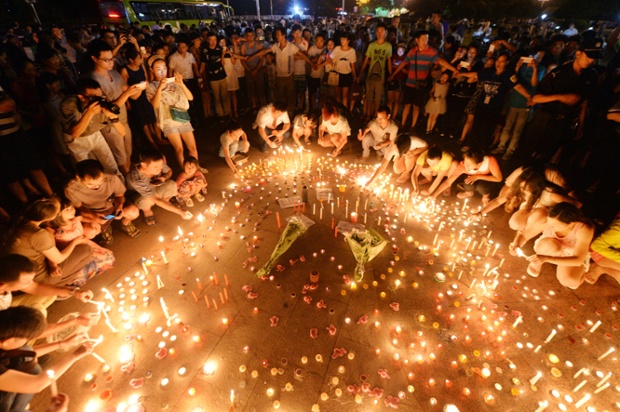 People light candles and pray for victims of a factory blast in Kunshan