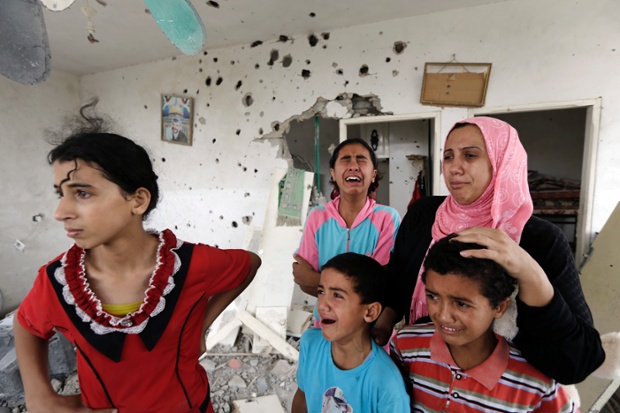 Salwa Shabat, right, accompanied by some of her children weep as they return to the family house, destroyed by Israeli strikes in the town of Beit Hanoun.