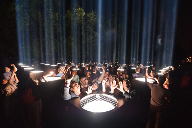 Members of the public enjoy 'Spectra', an art installation by Ryoji Ikeda as it lights the night sky