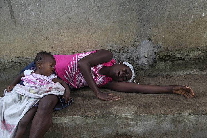 20 Photographs: A Liberian woman weeps over the death of a relative from Ebola