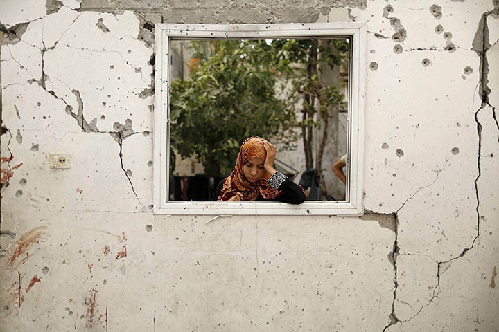 20 Photographs: A woman looks at a badly damaged house at the Jabaliya refugee camp