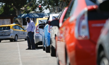 A cab driver waits near his car in line at a depot near the airport in San Diego. 
