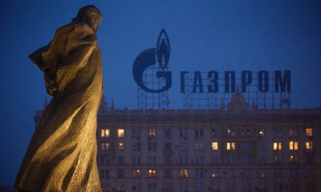 A monument to Ukrainian poet and writer Taras Shevchenko is silhouetted against an apartment building with a sign advertising Russia's natural gas giant Gazprom, in Moscow.