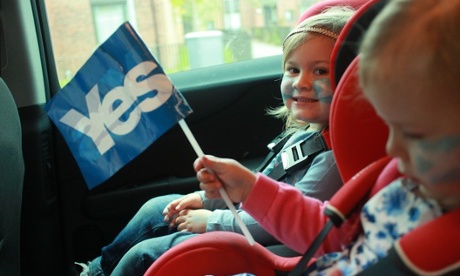 two young children in a car with painted faces one holding a yes flag