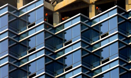 Workers install glass windows for a new building.