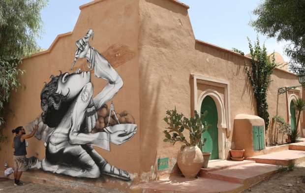 Brazilian artist Claudio Ethos works on his mural as part of the street art project 'Djerbahood'