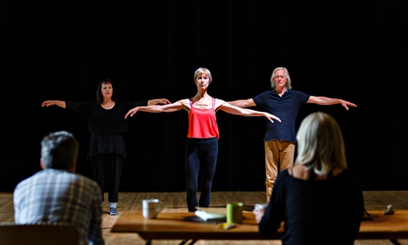 Three dancers, two female, one male, on stage with their arms stretched out to the side
