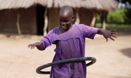 A child playing hula hoop with a tyre in the village of Olocoi.
