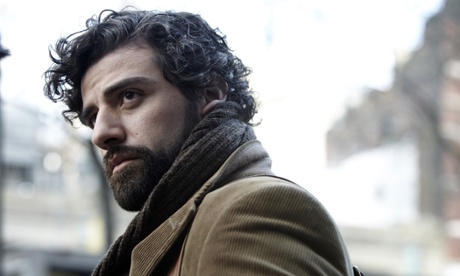 Oscar Isaac bearded and wearing a scarf and coat in a film still 