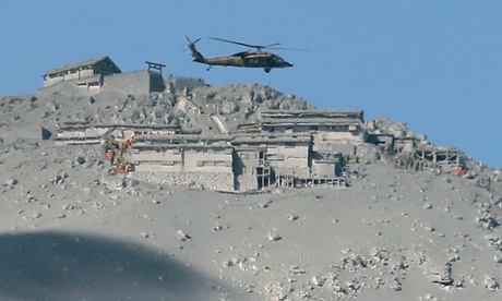 A rescue helicopter searches for survivors at the mountain shrine at the ash-covered summit of Mount Ontake.